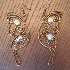 two pairs of earrings sitting on top of a wooden table