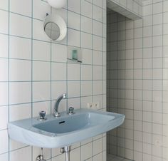 a bathroom sink sitting next to a white tiled wall