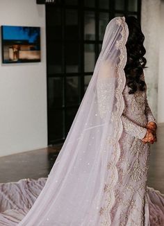 a woman in a wedding dress standing on a bed with her veil over her head