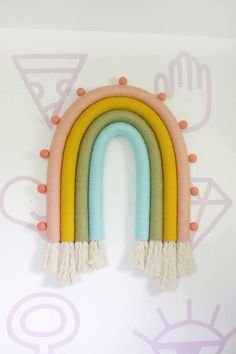 a rainbow shaped wall hanging with tassels on it