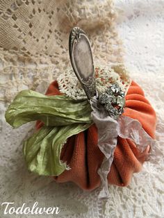 an orange and green flower on top of a white lace table cloth with a spoon in it