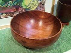 a wooden bowl sitting on top of a table next to two vases and a painting