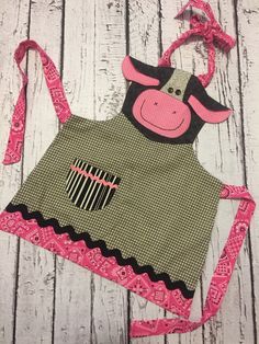 an apron with a cow on the front and pink trimmings around the neck