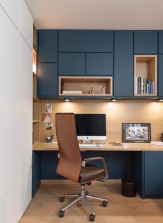 an office with blue cabinets and a brown chair in front of the desk is shown