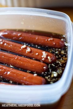 several hot dogs in a container with sesame seeds