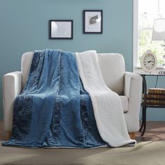 a living room with blue walls and a white couch covered in a blanket that is draped over it