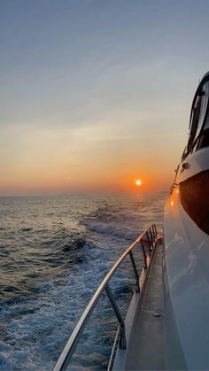 the sun is setting over the ocean on a boat