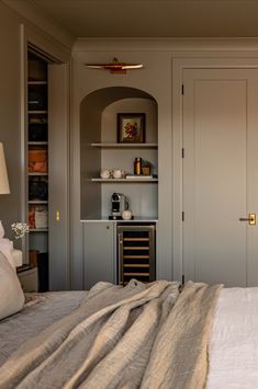 a bed with a blanket on top of it next to a wine rack and cabinets