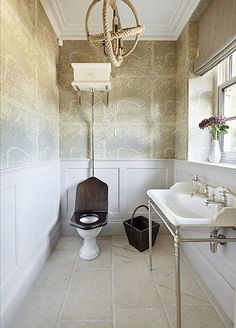 a bathroom with a toilet, sink and mirror next to a wallpapered wall