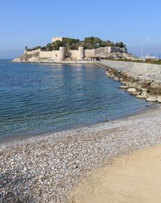 there is a small island in the middle of the water and rocks on the beach