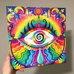 a person holding up a colorful art piece with an eye on the front and side