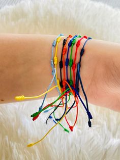 a woman's arm with several bracelets on it, all in different colors