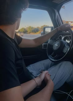 a man sitting in the driver's seat of a car with his hands on the steering wheel