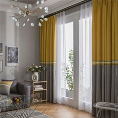 a living room with yellow drapes and curtains on the windowsill, along with a gray couch