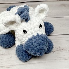 a blue and white crocheted stuffed animal laying on top of a wooden floor