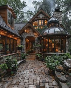 a stone walkway leads up to a large house with lots of windows and lights on the roof