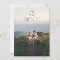 save the date card with an image of two people walking up a hill in the distance