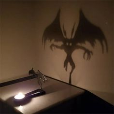 a shadow of a demon on the wall behind a desk with a pen and paper clip