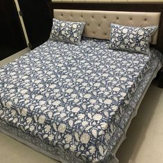 a bed with blue and white bedspread in a store display area next to a window