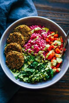 a bowl filled with meat patties, veggies, and other food items