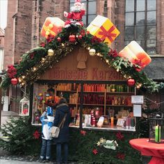 two people standing in front of a store with christmas decorations on the outside and inside