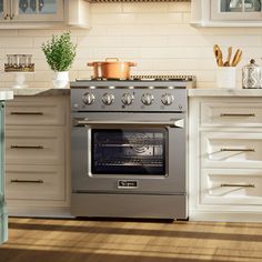 an oven in the middle of a kitchen with white cabinets and wood flooring on the walls