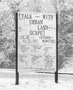 a black and white photo of a sign in front of some trees with snow on it