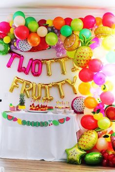 a party with balloons, pineapples and fruit