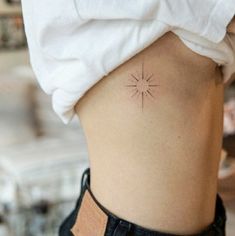 a woman with a small sun tattoo on her lower back side ribcacture