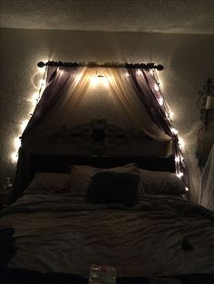 a bed that has some lights on the headboard and is lit up with fairy lights