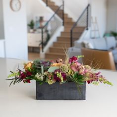 a vase filled with flowers sitting on top of a table next to a stair case