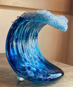 a blue glass wave sculpture sitting on top of a wooden table