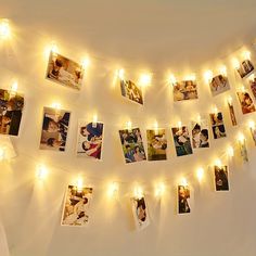 several pictures are hung on the wall with lights strung from them and some photos have been taken