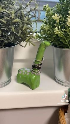 a green giraffe figurine sitting next to potted plants