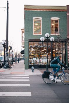 a person riding a bike down the street in front of a store with many windows