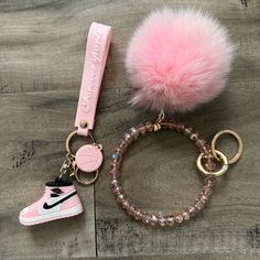 a pink keychain with a pair of sneakers and a pom - pom