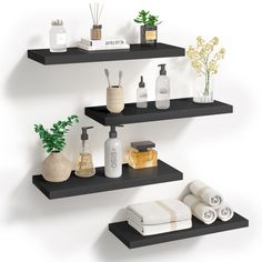 three black shelves with white towels, soaps and other personal care items on them