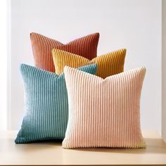 four pillows sitting on top of a table next to each other in different colors and sizes