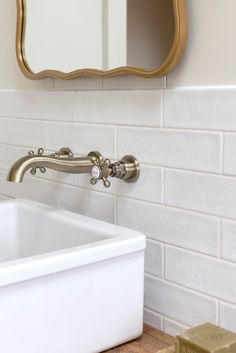 a white sink sitting under a bathroom mirror next to a bathtub and soap dispenser