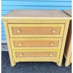 two yellow wicker dressers sitting next to each other in front of a blue wall