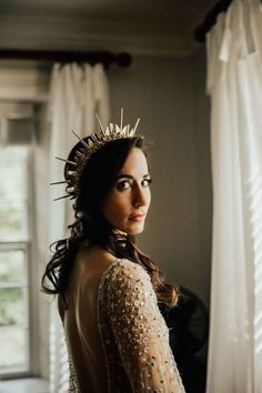 a woman wearing a crown standing in front of a window