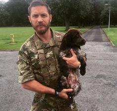 a man in camouflage holding a small animal