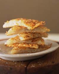 a stack of food sitting on top of a white plate next to a wooden table