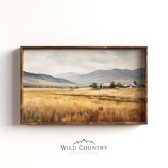 a painting hanging on the side of a wall next to a wooden framed sign that reads wild country