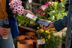 two people holding cell phones in their hands while one person holds a coffee cup and the other is holding a flower pot