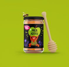 a jar of honey with a wooden spoon next to it on a bright green background