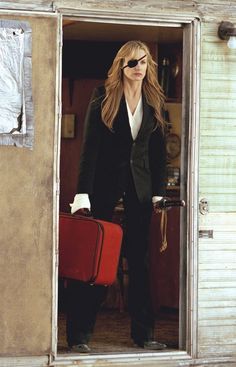 the woman is holding a red suitcase in her hand and looking into the open door