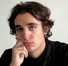 a close up of a person sitting at a table with a ring on his finger