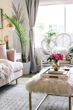 a living room filled with furniture and flowers on top of a table in front of a window