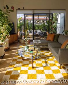 a living room filled with furniture and lots of plants on top of a wooden floor